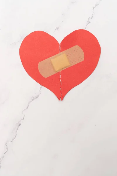 Abstract concept of love. Broken paper heart with medical health patch.