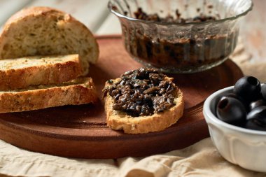 Black Olive Tapenade in bowl with spoon and Bread.