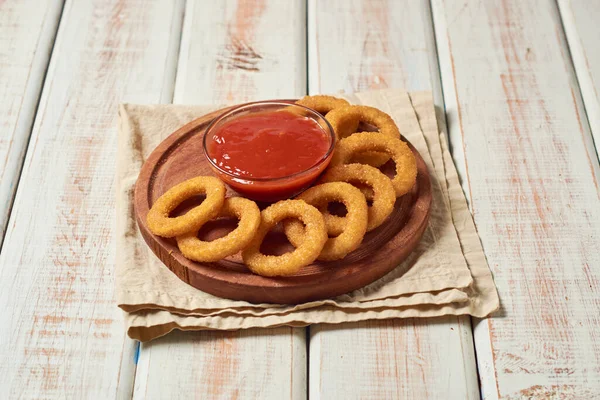 Plate of crunchy onion rings with ketchup sauce