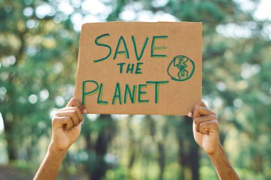 Young latin teenage man protests in the forest to save the planet.