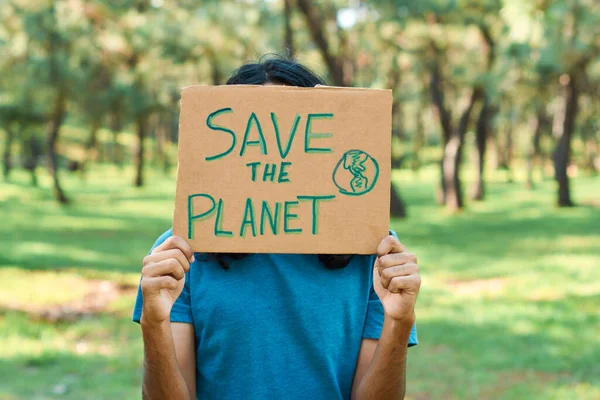 Young latin teenage man protests in the forest to save the planet.