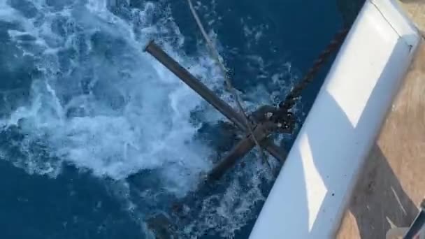 大きな鉄のアンカーは アンカーチェーンからぶら下がり ヨットが水を通過するときに波を打つ — ストック動画