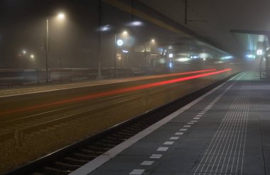 Sisli bir akşamda tren istasyonunda boş bir platformdan geçiyor. Groningen, Hollanda.