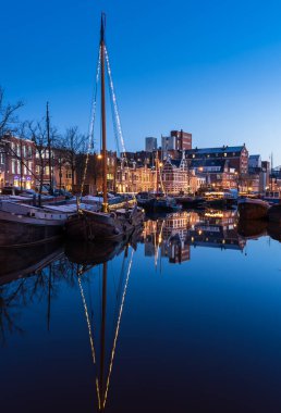 GRONINGEN - NETHERLANDS, 21 Aralık 2021: Groningen şehrindeki Noorderhaven 'da mavi saat boyunca yansımalar.