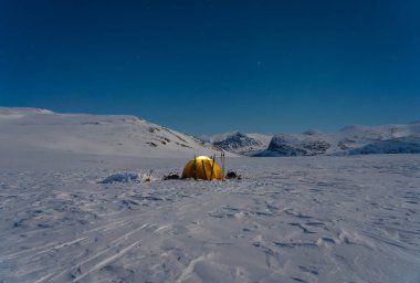 Laponya 'da güzel bir kış gecesinde dağlarda sarı çadır.