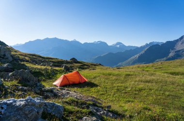 Red tent on a beautiful, tranquil campsite in the Swiss mountains.