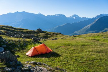 Red tent on a beautiful, tranquil campsite in the Swiss mountains.