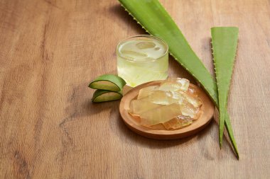 Yeşil yapraklı ahşap bir tabakta Aloe vera suyu, yiyecek ve içecek reklamları için ön manzara, yiyecek içeriği