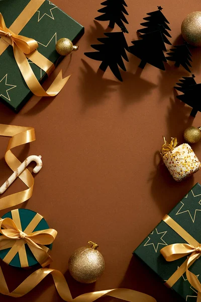 茶色の背景に濃い緑のクリスマスの装飾のトップビュー 黄色のリボン松の木とキラキラ黄色の真珠とギフトボックス休日の広告のための中央空白のスペース — ストック写真