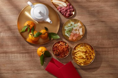Mandarin portakallı çaydanlık, altın çanak şeker reçeli, kızarmış patates çiçeği kırmızı cep bisküvisi, ahşap arka plan fotoğrafı Tet tatil içeriği, Çin yeni yılı