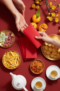 Mandarin portakal şekeri reçeli, kızarmış patates çaydanlığı, çiçek ve kırmızı cep bisküvisi ile altın tabak içinde Çin yeni yılı, fotoğrafçılık, tatil içeriği, üst görünüm