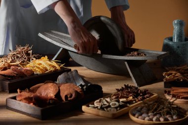 Kahverengi ahşap arka planda bitki ve baharatlı geleneksel Çin tıbbı ve Çin tıbbı içerikli reklamlar için bir doktor.