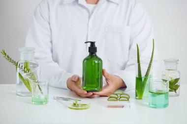 Aloe Vera laboratuvarda, petri kabı beyaz arka planda, yeşil yaprak test tüpünde ve bilim adamı kozmetik kavanozu reklamı, bilim konsepti