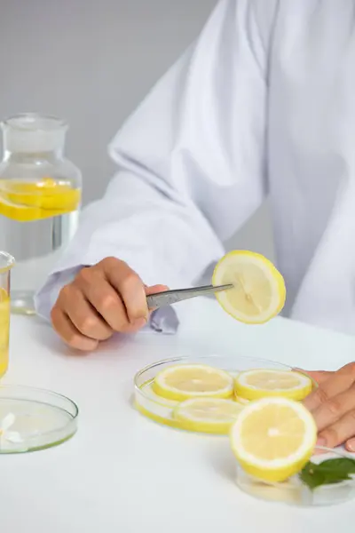 White Background with a scientist for Biological experiment presentation lemon extract and yellow water in biological test tubes. Production of cosmetics based on lemon