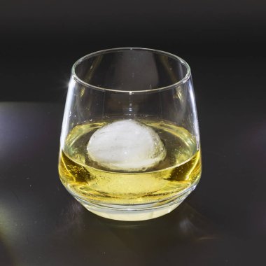 Buzlu viski, yuvarlak bir bardakta. Stüdyo fotoğrafı gibi, siyah arka planda.