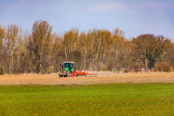 Op een landbouwveld ploegt een tractor met een ploeg het akkerland in de winter in de zon — Stockfoto