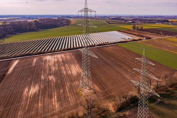 Electricity pylons and a solar park with PV modules in the middle of fields and meadows in the energy transition in Germany