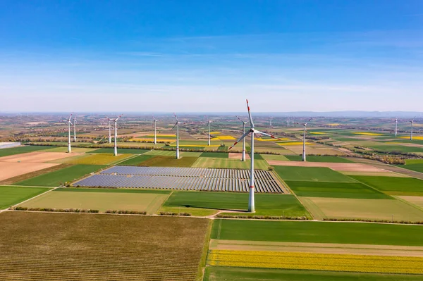 Electricity generation with wind turbines and solar park between fields from a drone perspective