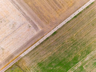 Fields after harvest are dried up and tractor tracks form natural lines and patterns from drone perspective