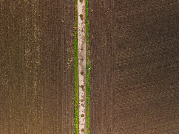 湿った肥沃な土地を有するコンクリート分割フィールドで作られた空中ビュー未舗装道路 — ストック写真