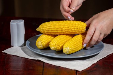 Gri tabakta kaynamış tatlı mısır serpiştirilmiş tuz 