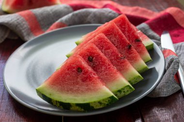 Gri tabaktaki ahşap masada tatlı sulu kırmızı karpuz