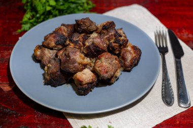 Shashalyk - kömürde kızartılmış domuz eti parçaları arpacık soğanı, sos ve siyah arka planlı bir tepside otlar..