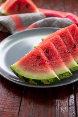 Gri tabaktaki ahşap masada tatlı sulu kırmızı karpuz