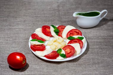 Caprese - mozzarella, domates, yeşil fesleğen beyaz bir tabakta soslu