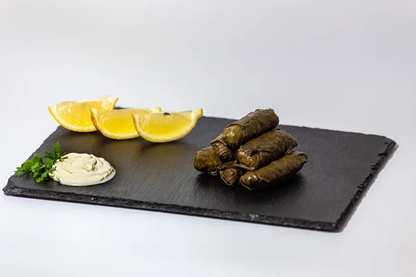 Traditionell georgiansk dolma med gräddfil och örter på svart skiffertavla, citron, koriander — Stockfoto