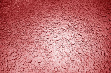 Metal yüzeyine kırmızı tonda su damlıyor. Tasarım için soyut arkaplan ve doku.