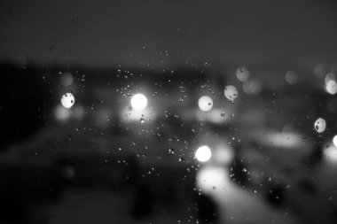 Gece şehrinde yağmur damlalarının olduğu pencereden bak. Bulanık arkaplan                                 