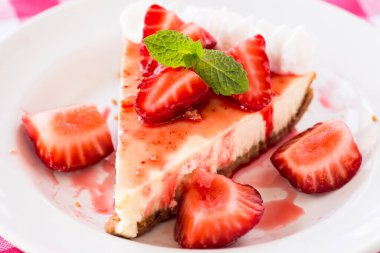 Taze kesilmiş çilek ve krem şantili bir dilim cheesecake 'in yakın plan makro fotoğrafı.