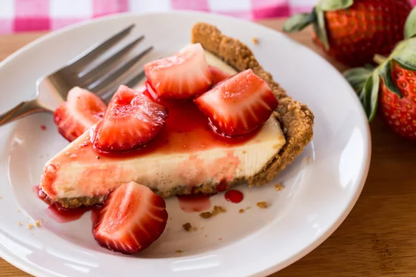 Beyaz tabakta dilimlenmiş çilekli cheesecake diliminin yakın çekim makrosu.