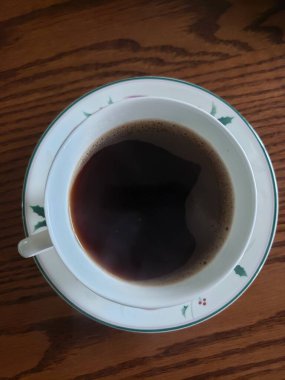 Tahta masadaki bir fincan koyu kahvenin kuş bakışı görüntüsü.