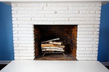 Mavi duvarlara karşı beyaz bir şömine.