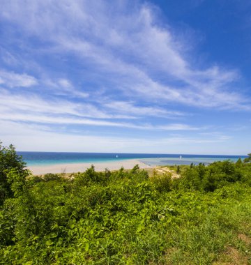 Bulutları, kumsalı ve ormanı olan yeşil ve mavi deniz