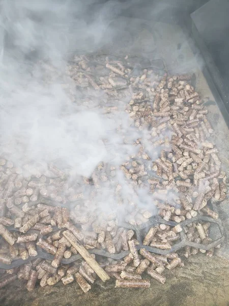Pellets in a hopper of a smoker/grill with smoke flowing out