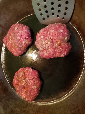 Tavada spatulayla pişen hamburgerler.