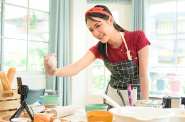 Güzel bir Asyalı kadın evinde fırın yapıyor, canlı yayın yapıyor ya da sosyal medyada video kaydediyor.  