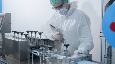 Modern fabrikada cerrahi maske üreten işçiler, Covid-19 koruma ve tıbbi konsept.