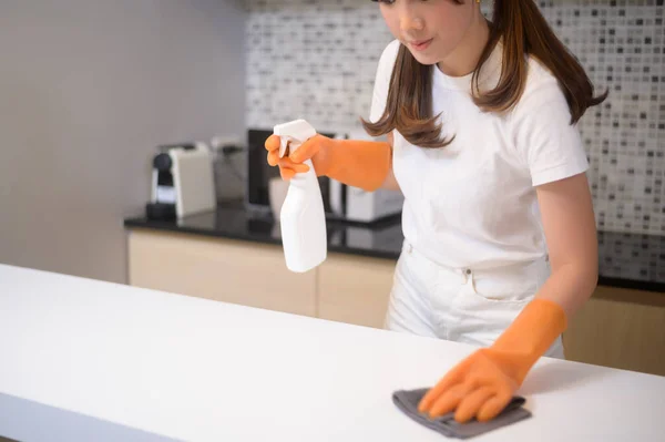 保護ゴム手袋を身に着けている若い美しい女性は自宅でキッチンでテーブルを掃除しています — ストック写真