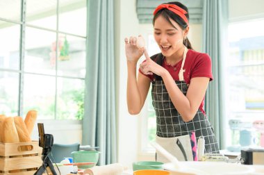 Güzel bir Asyalı kadın evinde fırın yapıyor, canlı yayın yapıyor ya da sosyal medyada video kaydediyor.  