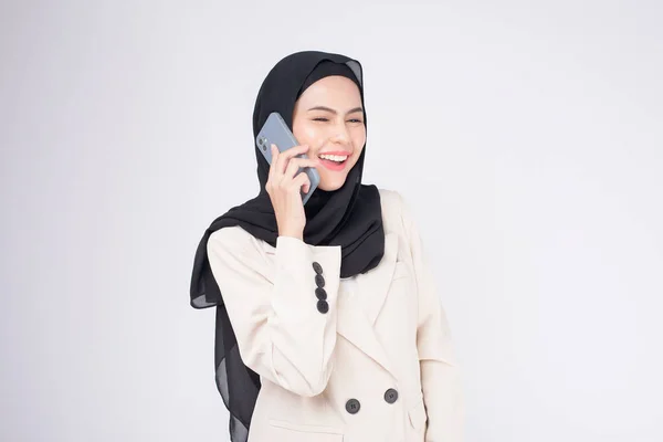 穿着西服的年轻漂亮的穆斯林女子的画像 用智能手机而不是白色背景 — 图库照片