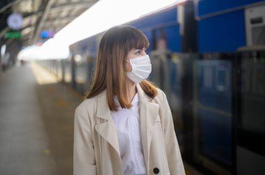 Genç bir kadın metro, covid-19 koruma, güvenlik seyahati, yeni normal, sosyal mesafeler, güvenlik ulaşımı, pandemik konsept altında seyahat ederken koruyucu maske takıyor