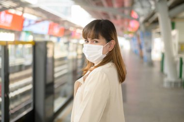 Genç bir kadın metro, covid-19 koruma, güvenlik seyahati, yeni normal, sosyal mesafeler, güvenlik ulaşımı, pandemik konsept altında seyahat ederken koruyucu maske takıyor
