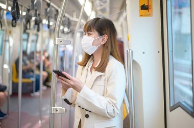 Genç bir kadın metro, covid-19 koruma, güvenlik seyahati, yeni normal, sosyal mesafeler, güvenlik ulaşımı, pandemik konsept altında seyahat ederken koruyucu maske takıyor