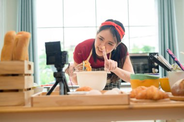 Güzel bir Asyalı kadın evinde fırın yapıyor, canlı yayın yapıyor ya da sosyal medyada video kaydediyor.  