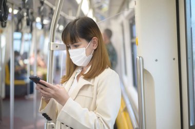Genç bir kadın metro, covid-19 koruma, güvenlik seyahati, yeni normal, sosyal mesafeler, güvenlik ulaşımı, pandemik konsept altında seyahat ederken koruyucu maske takıyor
