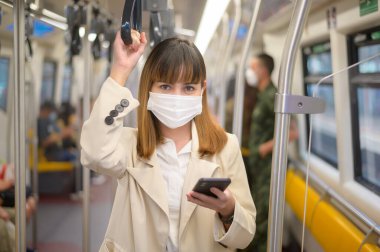 Genç bir kadın metro, covid-19 koruma, güvenlik seyahati, yeni normal, sosyal mesafeler, güvenlik ulaşımı, pandemik konsept altında seyahat ederken koruyucu maske takıyor